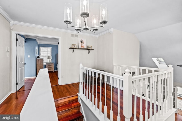 corridor with a chandelier, a skylight, wood finished floors, visible vents, and ornamental molding