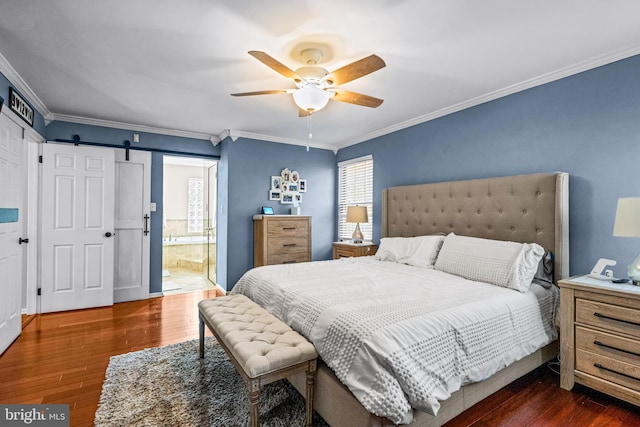 bedroom featuring ornamental molding, a barn door, dark wood-type flooring, and connected bathroom