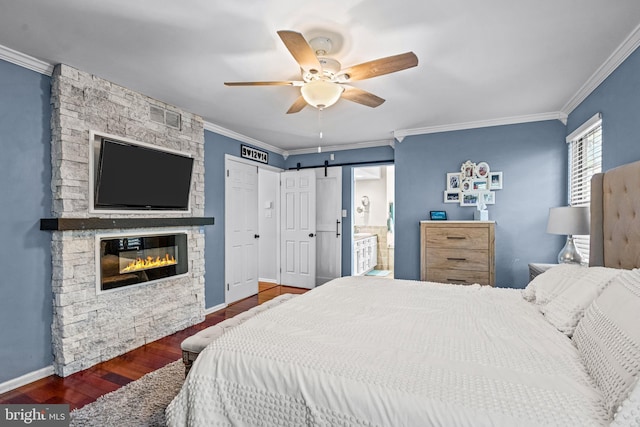 bedroom featuring baseboards, a barn door, ornamental molding, and wood finished floors