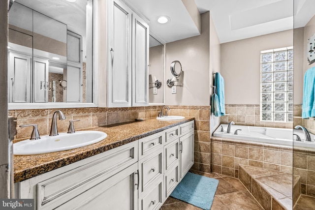 full bath featuring a bath, tile patterned flooring, double vanity, and a sink