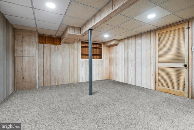 finished below grade area with a paneled ceiling, wooden walls, carpet flooring, and recessed lighting