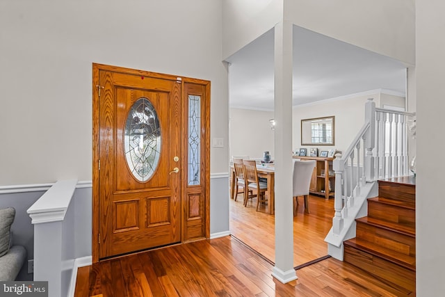 foyer entrance featuring baseboards, stairway, wood finished floors, and crown molding