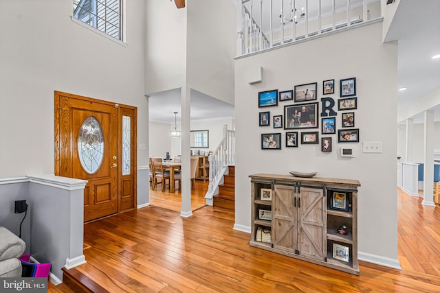 entryway with stairs, a towering ceiling, hardwood / wood-style flooring, and baseboards