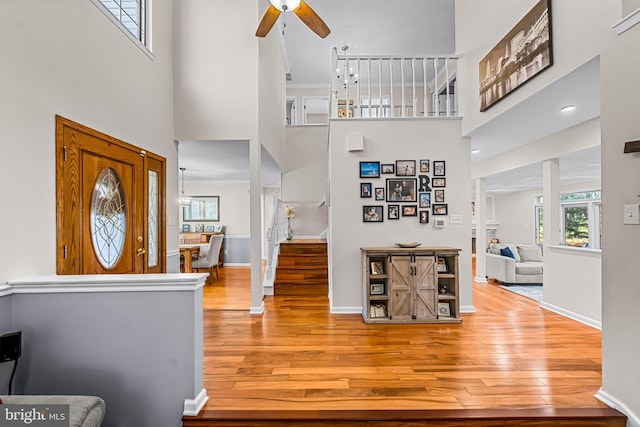 foyer entrance with a towering ceiling, baseboards, stairway, and hardwood / wood-style floors