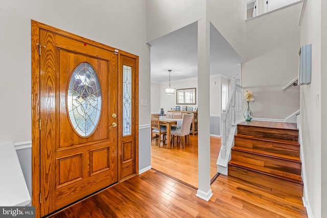 entryway with stairway, a towering ceiling, ornamental molding, wood finished floors, and baseboards