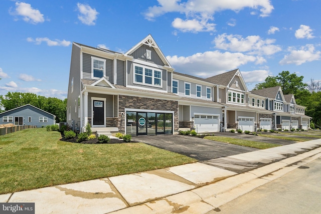 multi unit property with a garage, stone siding, driveway, a front lawn, and board and batten siding