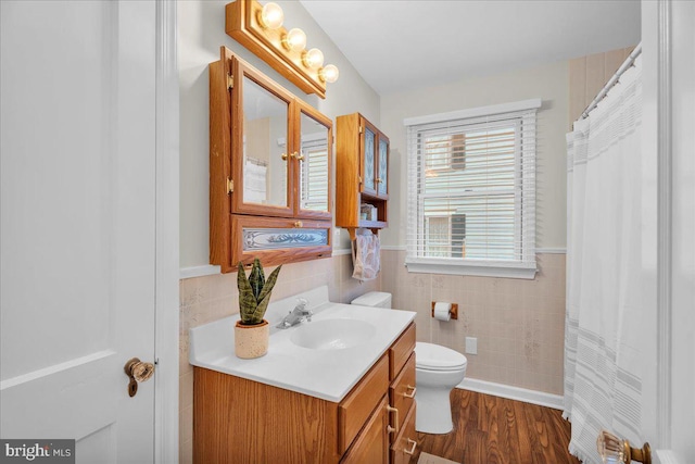 full bathroom featuring a wainscoted wall, tile walls, toilet, vanity, and wood finished floors