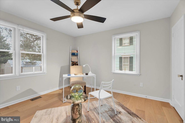 office featuring a ceiling fan, visible vents, baseboards, and wood finished floors