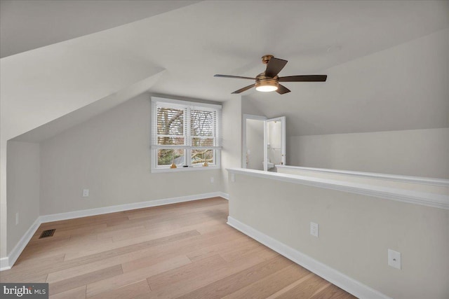 additional living space with vaulted ceiling, wood finished floors, visible vents, and baseboards