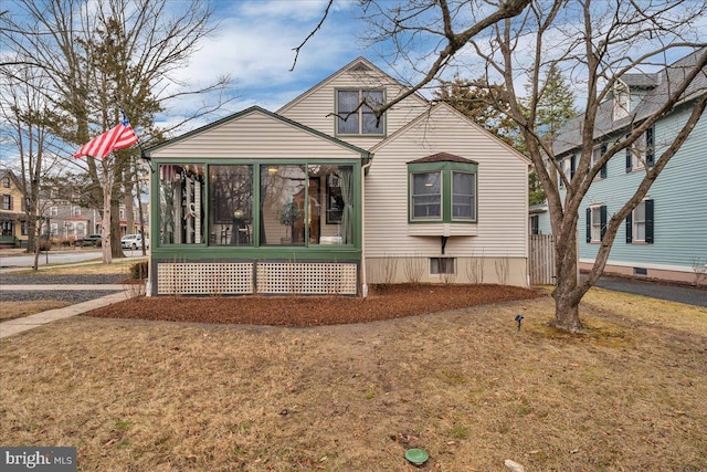 view of front of house with a front yard and a sunroom