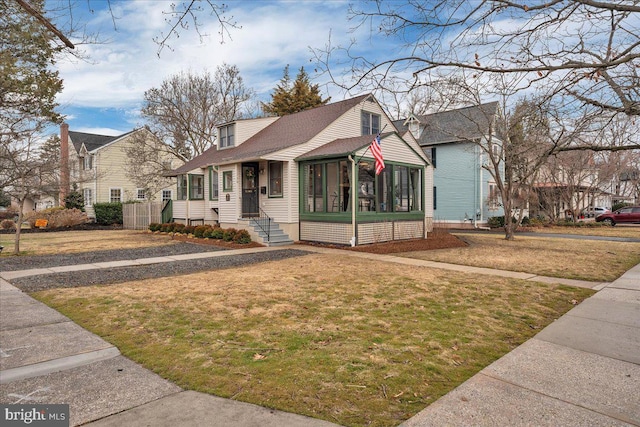 bungalow-style home featuring a sunroom and a front lawn