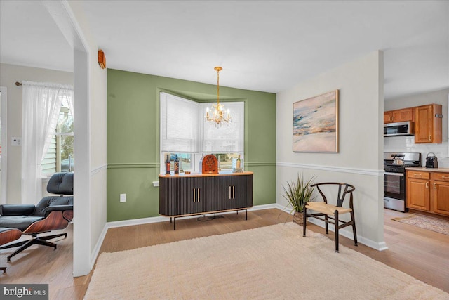 sitting room with a chandelier, light wood-style flooring, and baseboards