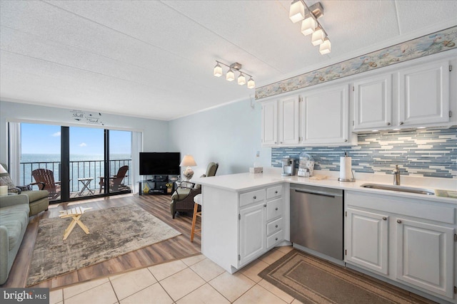 kitchen featuring open floor plan, dishwasher, a peninsula, and a sink