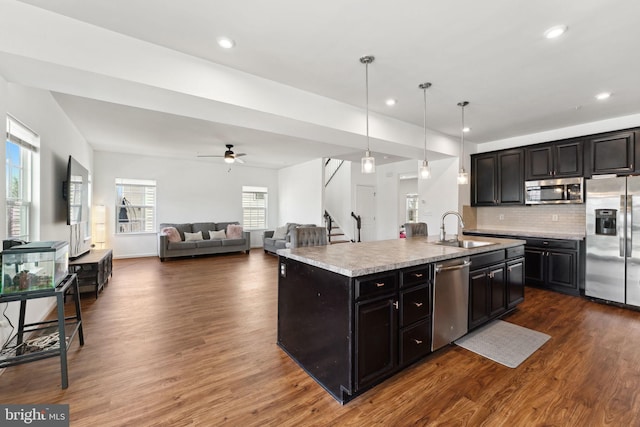 kitchen with light countertops, tasteful backsplash, a sink, dark wood-style floors, and appliances with stainless steel finishes