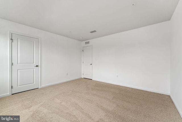 carpeted spare room featuring baseboards and visible vents