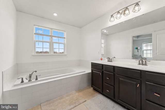 full bathroom featuring a healthy amount of sunlight, double vanity, a bath, and a sink