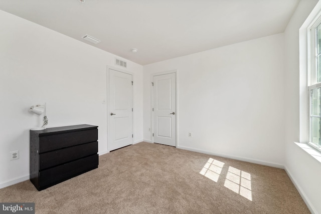 unfurnished bedroom with carpet flooring, baseboards, and visible vents