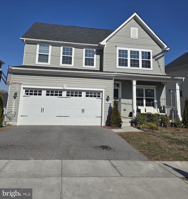 traditional home featuring an attached garage, covered porch, and driveway