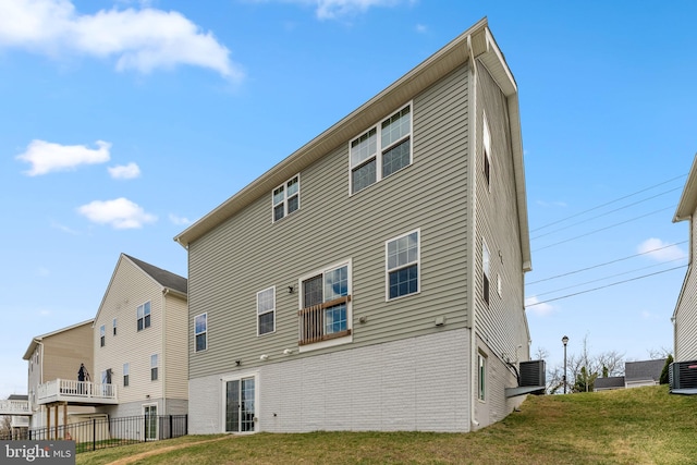 rear view of house featuring central air condition unit, a lawn, fence, and brick siding