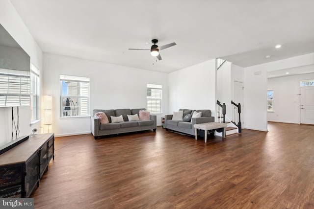 living room with dark wood-type flooring, a healthy amount of sunlight, stairs, and ceiling fan
