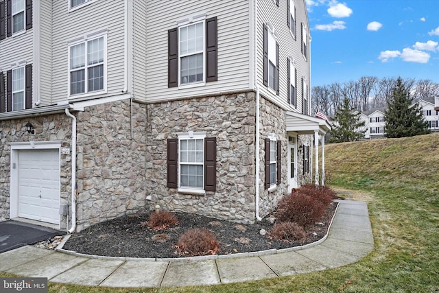 view of home's exterior with an attached garage and stone siding