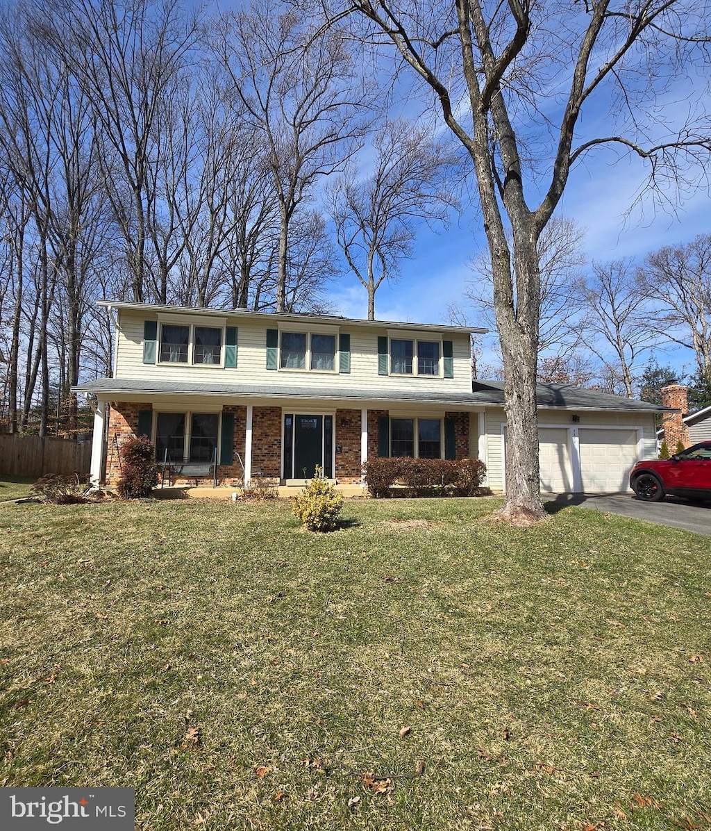 view of front of home with aphalt driveway, a front yard, brick siding, and an attached garage