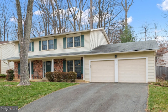 traditional-style house featuring brick siding, fence, aphalt driveway, a front yard, and a garage