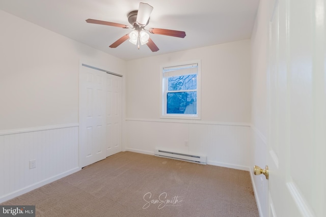 unfurnished room featuring carpet, baseboard heating, and wainscoting