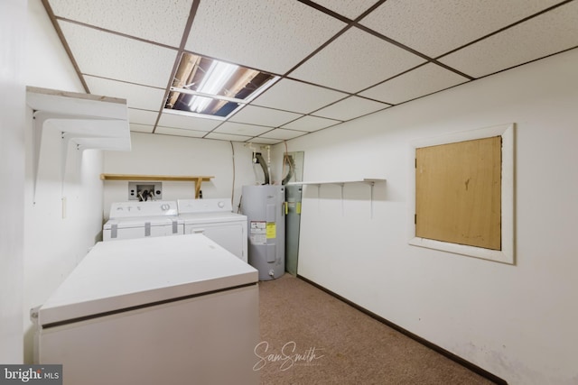 clothes washing area with water heater, washing machine and dryer, and baseboards