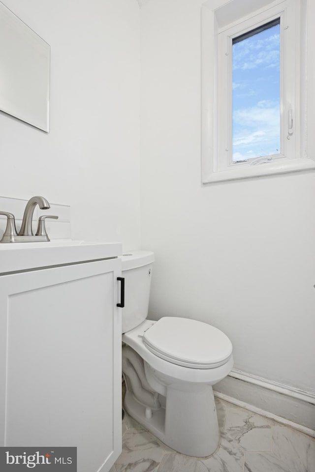 bathroom featuring toilet, marble finish floor, and vanity