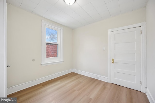 unfurnished room with light wood-type flooring and baseboards