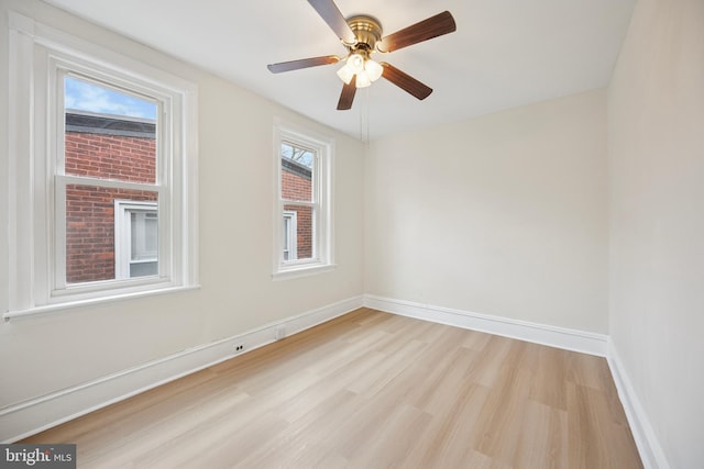 spare room featuring light wood finished floors, baseboards, and a ceiling fan