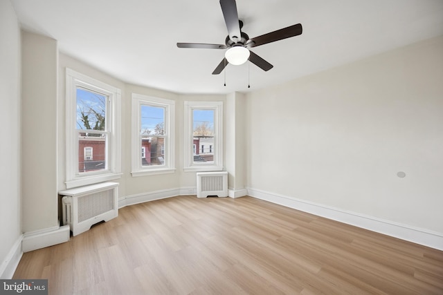 spare room with radiator, a healthy amount of sunlight, and light wood-type flooring