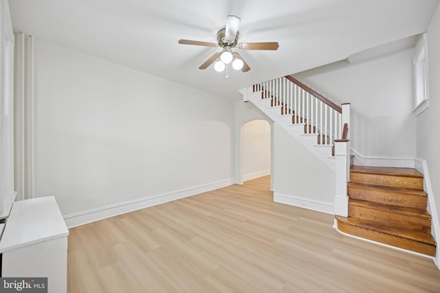 unfurnished living room featuring light wood-style floors, stairway, baseboards, and a ceiling fan