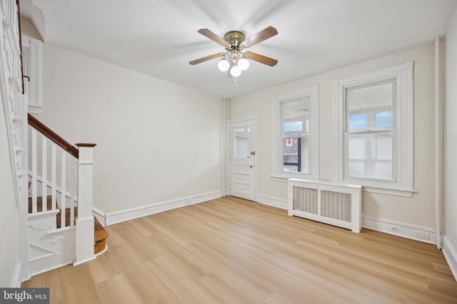 foyer with radiator, stairs, baseboards, and wood finished floors