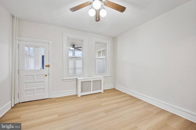 entrance foyer featuring baseboards, a ceiling fan, light wood-style flooring, and radiator