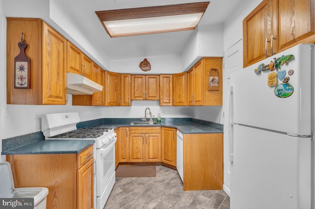 kitchen with dark countertops, white appliances, under cabinet range hood, and a sink