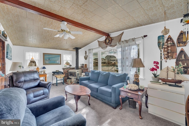 living room with carpet floors, a wood stove, lofted ceiling with beams, and a ceiling fan