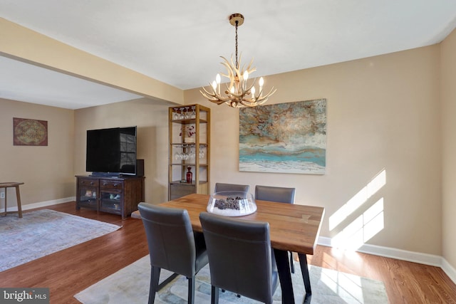 dining room with a chandelier, baseboards, and wood finished floors