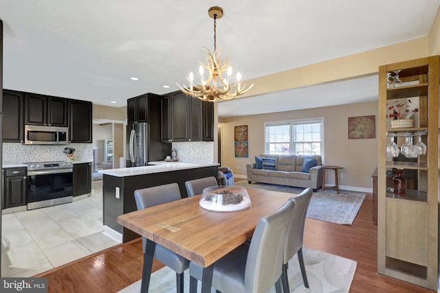 dining area featuring light wood-style floors, recessed lighting, a notable chandelier, and baseboards