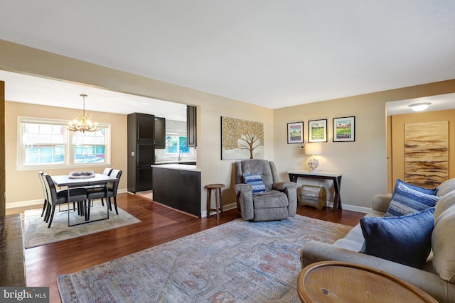 living area featuring baseboards, a chandelier, and wood finished floors