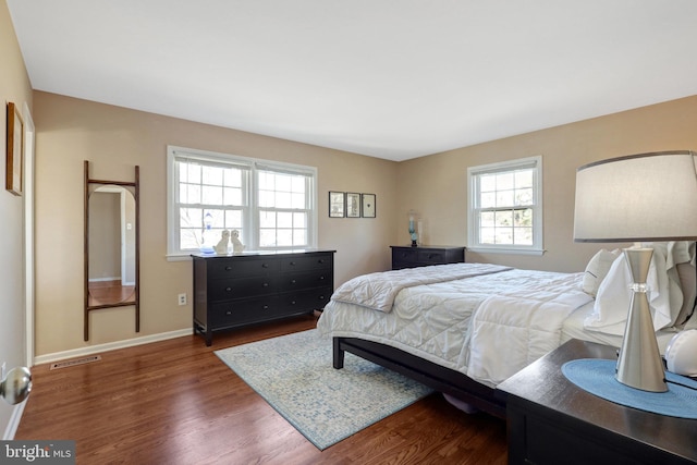 bedroom with visible vents, baseboards, and wood finished floors