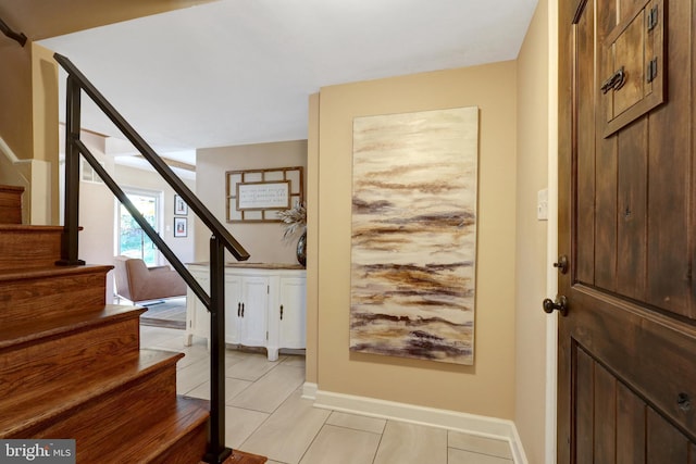 entrance foyer featuring light tile patterned floors, stairs, and baseboards