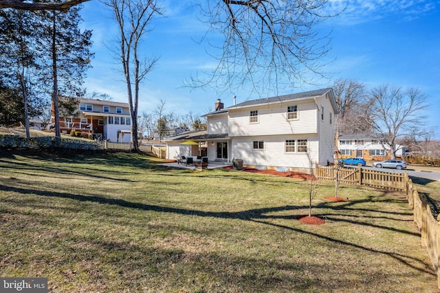 back of house featuring entry steps, a yard, a chimney, and fence