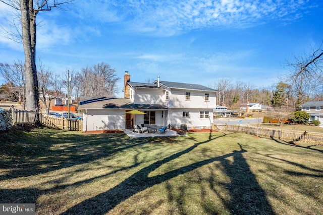 rear view of property featuring a patio area, a fenced backyard, a chimney, and a yard