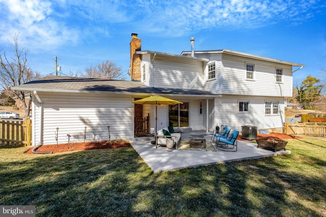 rear view of house featuring an outdoor fire pit, a lawn, a patio, a chimney, and fence