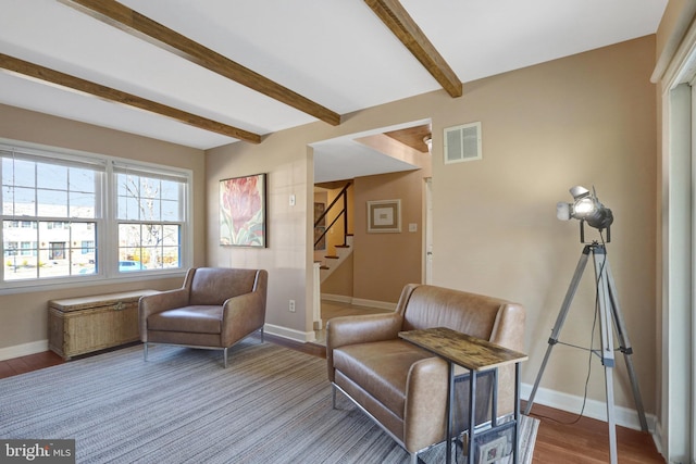 living area with baseboards, visible vents, beamed ceiling, wood finished floors, and stairs