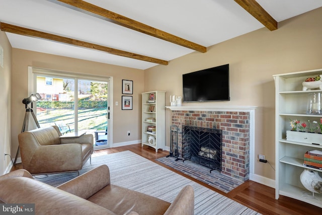 living room featuring a brick fireplace, beamed ceiling, baseboards, and wood finished floors