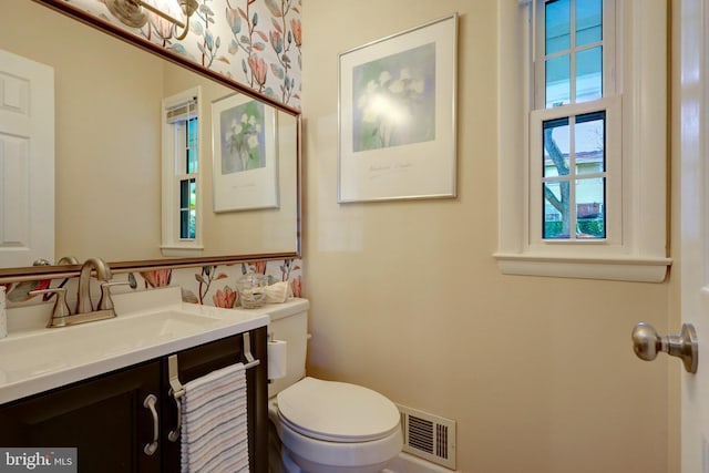 half bathroom with toilet, vanity, and visible vents