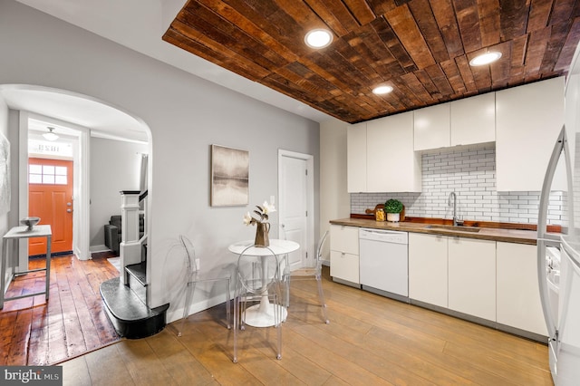 kitchen with light wood-style flooring, white cabinetry, white dishwasher, wood counters, and a sink